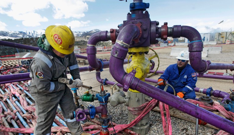 Workers tend to a well head during a hydraulic fracturing operation outside Rifle, in western Colorado.