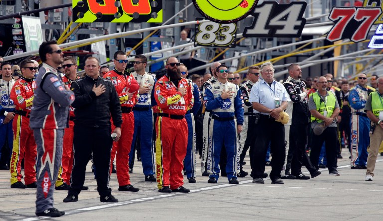 NASCAR teams crew members stand during the national anthem before a NASCAR Cup Monster Energy Series auto race at Chicagoland Speedway in Joliet, Ill., Sunday, Sept. 17, 2017.
