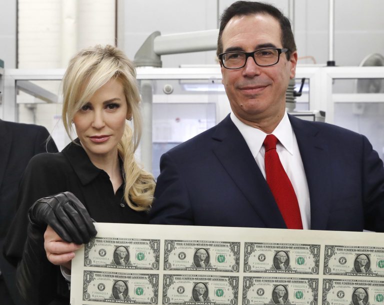 Treasury Secretary Steven Mnuchin, right, and his wife Louise Linton, hold up a sheet of new $1 bills, the first currency notes bearing his and U.S. Treasurer Jovita Carranza's signatures, Wednesday, Nov. 15, 2017, at the Bureau of Engraving and Printing (BEP) in Washington. The Mnuchin-Carranza notes, which are a new series of 2017, 50-subject $1 notes, will be sent to the Federal Reserve to issue into circulation. At left is BEP Director Leonard Olijar.