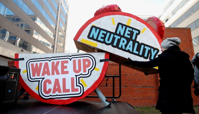 Sammi LeMaster helps to dismantle a large alarm clock display that reads "Net Neutrality Wake Up Call" from the stage after a protest at the Federal Communications Commission in D.C.