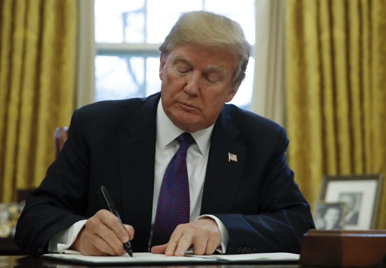 President Trump signs a document in the Oval Office of the White House in Washington.