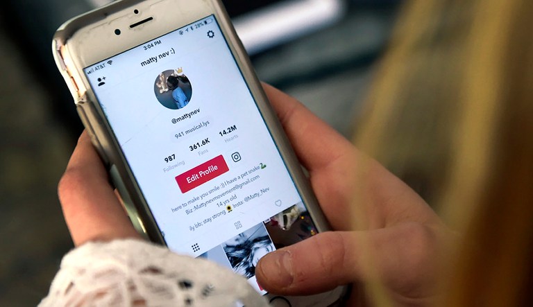 In this Feb. 28, 2018 photo, Matty Nev Luby holds her phone and logs into the lip-sync smartphone app Musical.ly, in Wethersfield, Conn.