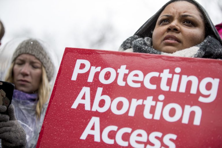 A pro-abortion rights supporter holds a sign that reads "Protecting Abortion Access" during a rally outside the Supreme Court in Washington, Tuesday, March 20, 2018, as the Supreme Court hears arguments in a free speech fight over California's attempt to regulate anti-abortion crisis pregnancy centers.
