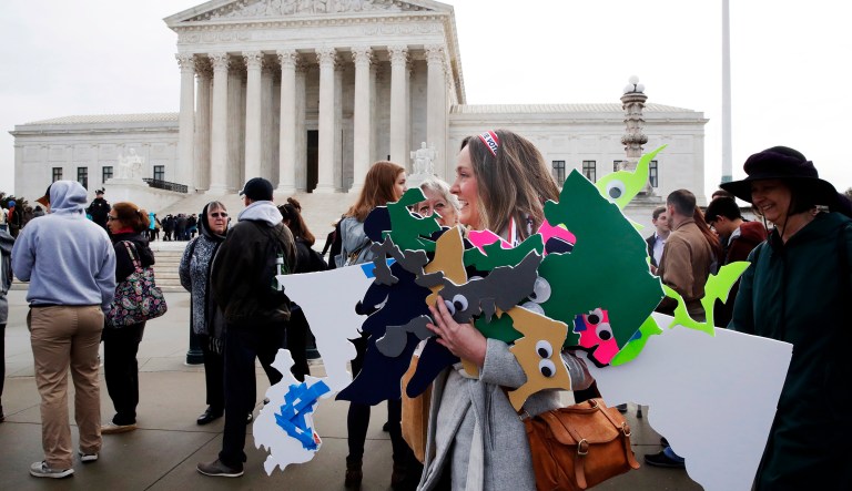 Ashley Oleson, with the League of Women Voters of Maryland, carries signs of Maryland's districts, as nonpartisan groups against gerrymandering protest in front of the Supreme Court in Washington.