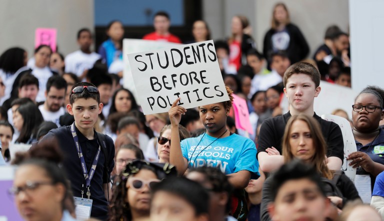 A student from Destiny Charter Middle School in Tacoma, Wash., holds a sign that reads "Students Before Politics," during a rally held by charter school students, teachers, and supporters at the state Capitol on May 17, 2018.