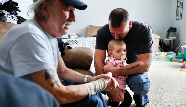 Tom Wolikow, right, holds his daughter Annabella alongside his father John, left, at their home in Warren, Ohio. It was working-class voters who bucked the area's history as a Democratic stronghold and backed Donald Trump in 2016, helping him win the White House with promises to put American workers first and bring back disappearing manufacturing and steel jobs. Whether they stick with him after this week's GM news and other signs that the economy could be cooling will determine Trump's political future.