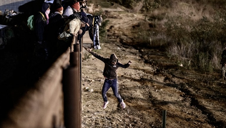 A migrant jumps the border fence to get into the U.S. side to San Diego, Calif.