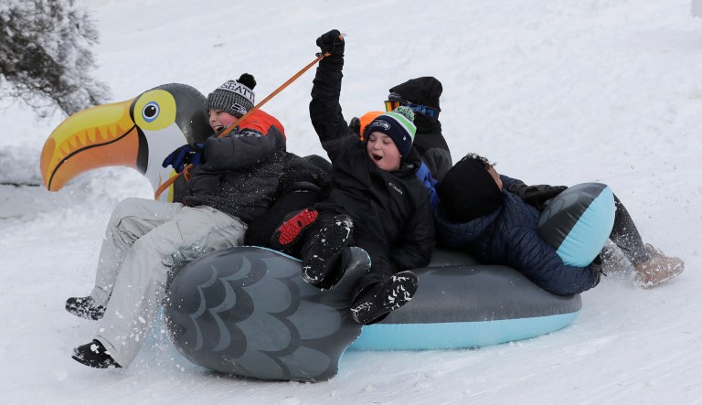 Sledders slide down a hill on an inflatable bird in Tacoma, Wash.