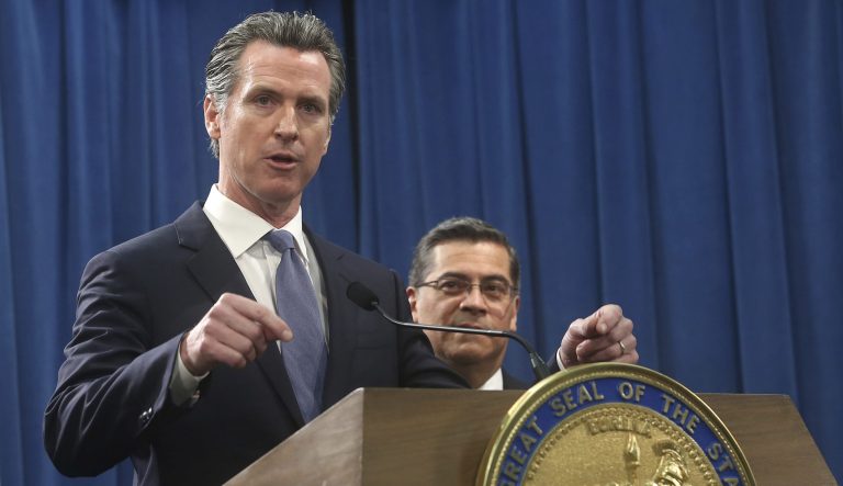 California Gov. Gavin Newsom, left, flanked by Attorney General Xavier Becerra, right, answers a question concerning a probable lawsuit the state will likely file against President Donald Trump over his emergency declaration to fund a wall on the U.S.-Mexico border Friday, Feb. 15, 2019, in Sacramento, Calif.