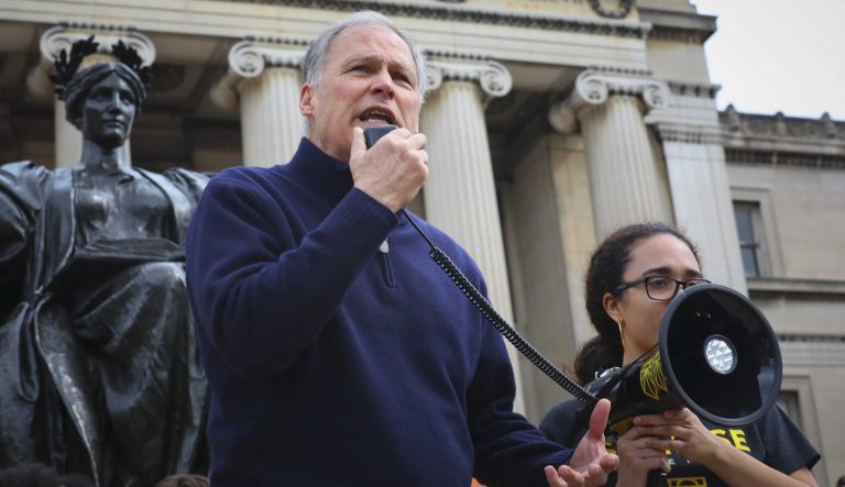 Student organizer Naomi Hollard, far right, holds a bullhorn for Democratic presidential candidate Washington Gov. Jay Inslee, as he address a Columbia Climate Strike rally at Columbia University, Friday March 15, 2019, in New York. 