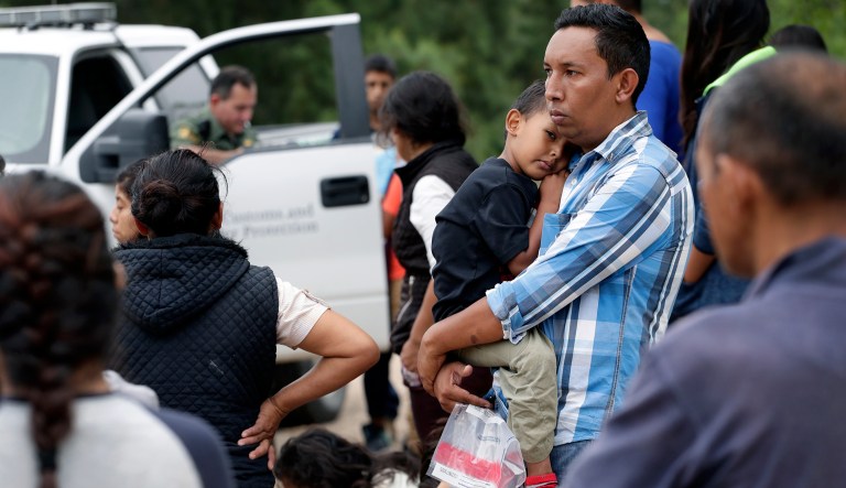 In this Thursday, March 14, 2019, photo, families who crossed the nearby U.S.-Mexico border near McAllen, Texas wait for Border Patrol agents to check names and documents. Immigration authorities say they expect the ongoing surge of Central American families crossing the border to multiply in the coming months. 