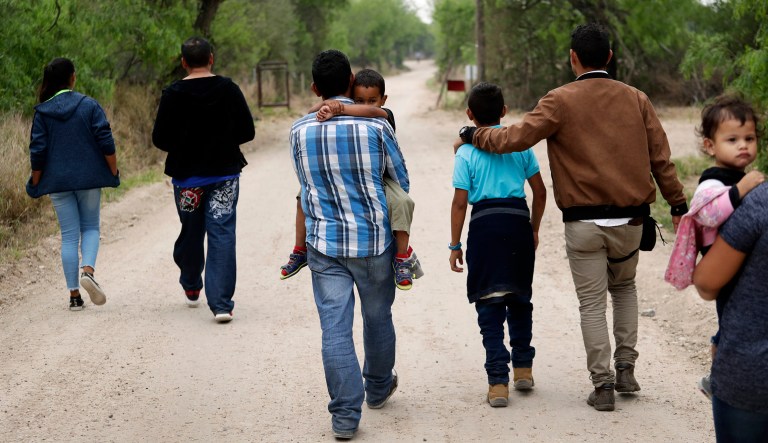 In this Thursday, March 14, 2019, photo, a group of migrant families walk from the Rio Grande, the river separating the U.S. and Mexico in Texas, near McAllen, Texas. The migrants said they crossed the river in an inflatable raft and were hoping to be apprehended by the Border Patrol so they could be processed and released.