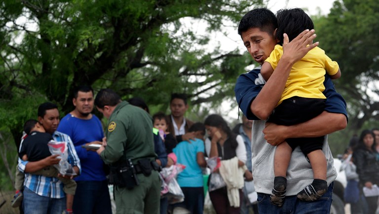 In this Thursday, March 14, 2019, photo, Jose Fermin Gonzalez Cruz holds his son, William Josue Gonzales Garcia, 2, as they wait with other families who crossed the nearby U.S.-Mexico border near McAllen, Texas.