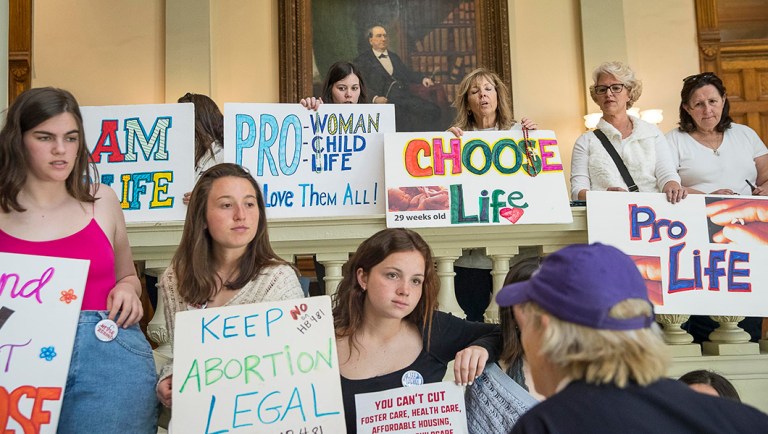 Pro-abortion rights and anti-abortion demonstrators displaying their signs in the lobby of the Georgia State Capitol building.