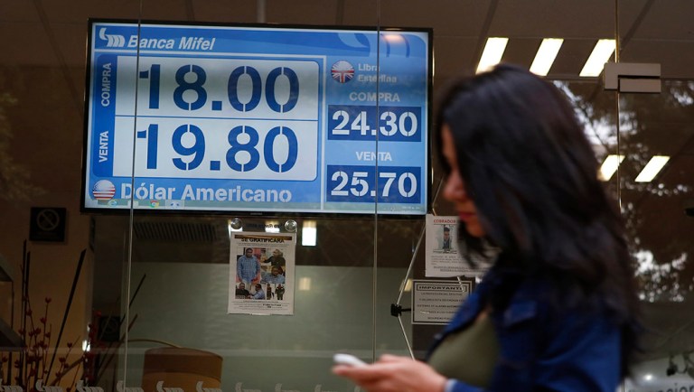 A sign displays exchange rates on a storefront window in Mexico City, Mexico.