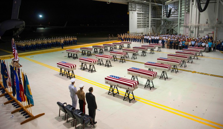 In this Wednesday, July 17, 2019 photo, service members and guests stand as "Taps" is played over transfer cases carrying the possible remains of unidentified service members lost in the Battle of Tarawa during World War II, during what is known as an honorable carry conducted by the Defense POW/MIA Accounting Agency, in a hangar at Joint Base Pearl Harbor-Hickam in Hawaii. The remains were recently recovered from the Republic of Kiribati by History Flight, a DPAA partner organization, and will be taken to a laboratory in Hawaii to begin the identification process. 