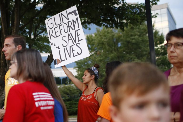 Protester Rosa Cox holds a sign outside the National Rifle Association's headquarters building during a vigil for recent victims of gun violence, Monday, Aug. 5, 2019, in Fairfax, Va.