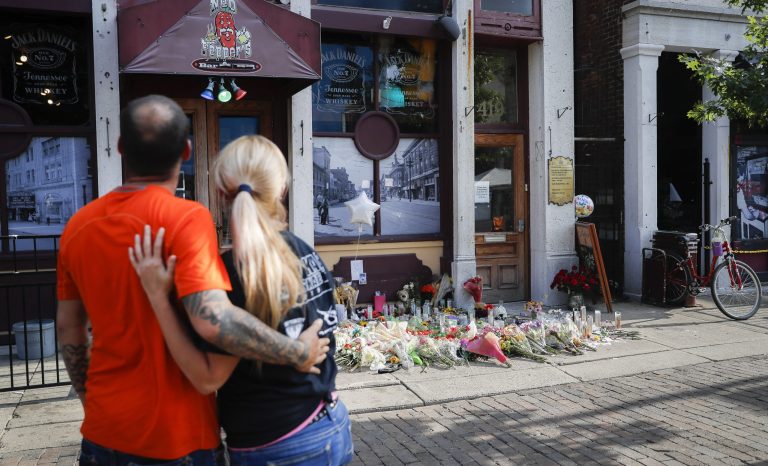 Mourners pause at a makeshift memorial for the slain and injured outside Ned Peppers bar in the Oregon District after a mass shooting that occurred early Sunday morning, Tuesday, Aug. 6, 2019, in Dayton. 