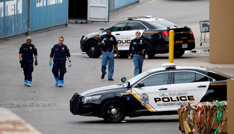 Police officers walk behind a Walmart at the scene of a mass shooting at a shopping complex in El Paso, Texas.