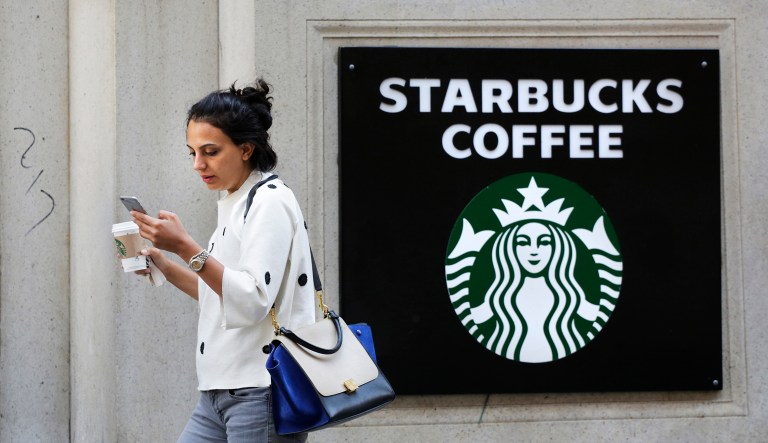 A woman walks out of a Starbucks Coffee with a beverage in hand in New York. Starbucks and Panera are each hyping reformulated versions of their pumpkin spice lattes in a fight to win over fans of the drink in coming weeks. Starbucks Corp. said Monday, Aug. 17, its version of the concoction this year will be made with real pumpkin and without caramel coloring.