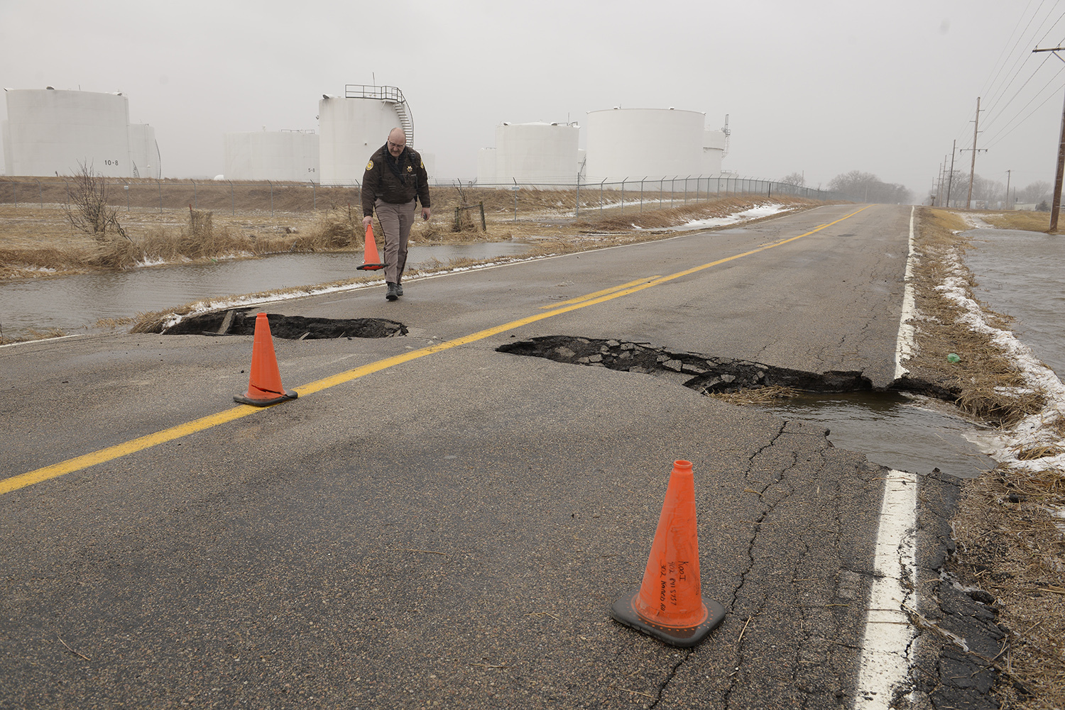 Madison County Sheriff Todd Volk replaces cones on an area of Kaneb Road north of Norfolk, Neb., that had washed out while making rounds checking on the flooding situation in the county. Thousands of people have been urged to evacuate along eastern Nebraska rivers as a massive late-winter storm has pushed streams and rivers out of their banks throughout the Midwest. 