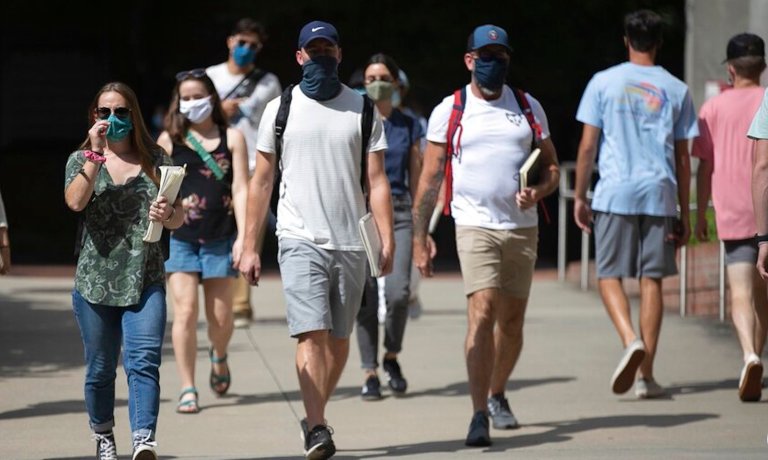 North Carolina State University students wearing face coverings walk behind Dabney Hall to the Free Expression Tunnel on Tuesday, Aug. 18, 2020 in Raleigh, N.C. The university announced Thursday, Aug. 20, 2020, it will move all undergraduate classes online starting on Monday due to COVID-19 clusters.