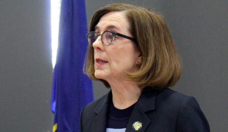 In this March 16, 2020, file photo, Oregon Gov. Kate Brown speaks at a news conference in Portland, Oregon, to announce a four-week ban on eat-in dining at bars and restaurants, due to COVID-19, throughout the state. As she was putting the finishing touches on a reopening plan in May, Oregon Gov. Kate Brown received a letter from a coalition of business groups pressing for more say in the process.