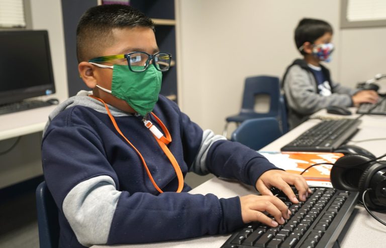 Masked students work on computers at Tibbals Elementary School in Murphy, Texas, Thursday, Dec. 3, 2020. Texas Gov. Greg Abbot's statewide mask order does not mandate face covering for children under the age of 10, allowing some school districts to not require masks for children leaving the choice of mask use up to the parents.