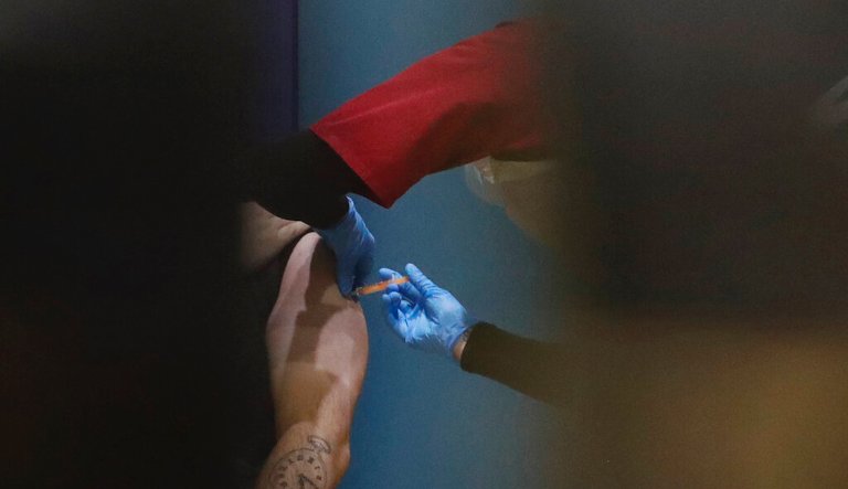 Apprentice Nursing's Associate Ellie Bull injects the AstraZeneca vaccine to a homeless person in Romford, east London, Wednesday, Feb. 3, 2021. The British health service has started to vaccinate "vulnerable" homeless people. In a study by Oxford University, the AstraZeneca vaccine has been shown to reduce transmission of the virus.