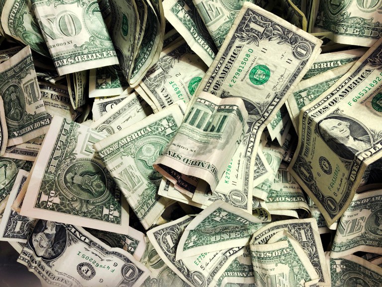 FILE - In this Jan. 21, 2020 file photo, dollar bills have been dropped into a tip jar at a carwash in the Brooklyn borough of New York. (AP Photo/Mark Lennihan, File)