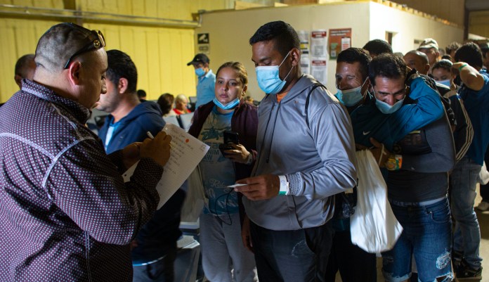 People line up for a commercial bus that will take them to the San Antonio airport at a warehouse run by the Mission: Border Hope nonprofit group run by the United Methodist Church in Eagle Pass, Texas, on May 23. The Border Patrol releases up to 1,000 migrants daily at Mission: Border Hope. The nonprofit group outgrew a church and moved to the warehouse in April amid the Biden administration's rapidly expanding practice of releasing migrants on parole, particularly those who are not subject to a pandemic rule that prevents migrants from seeking asylum.