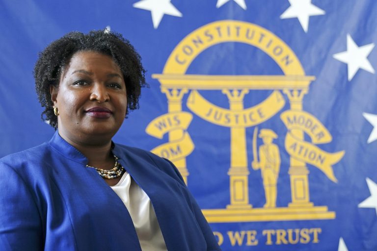 FILE - Democratic candidate for Georgia Governor Stacey Abrams poses for a portrait in front of the State Seal of Georgia in this Monday, August 8, 2022, in Decatur, Georgia. Abrams announced Wednesday, August 10, 2022 that she has tested positive for Covid-19 and is experiencing mild symptoms. (AP Photo/John Bazemore)