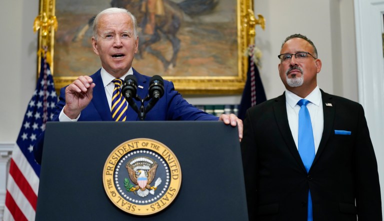 President Joe Biden speaks about student loan debt forgiveness in the Roosevelt Room of the White House, on Aug. 24, 2022, in Washington. Education Secretary Miguel Cardona listens at right.