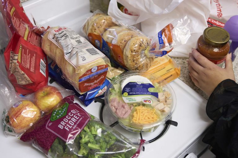 Jaqueline Benitez puts away groceries at her home in Bellflower, Calif., on Monday, Feb. 13, 2023. Benitez, 21, who works as a preschool teacher, depends on California's SNAP benefits to help pay for food, and starting in March she expects a significant cut, perhaps half, of the $250 in food benefits she has received since 2020. 