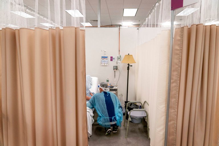 A physical therapist works with a patient at a field hospital operated by Care New England set up in a former bank call center to handle a surge of COVID-19 patients in Cranston, R.I, Dec. 14, 2020. 