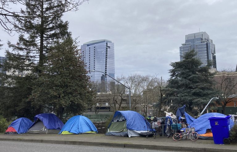 People camp in tents next to the Interstate 405 freeway in Portland, Ore., on March 31, 2023.