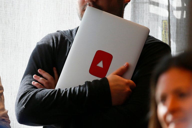 A man holds a laptop computer with a YouTube logo on it at YouTube Space LA offices in Los Angeles.