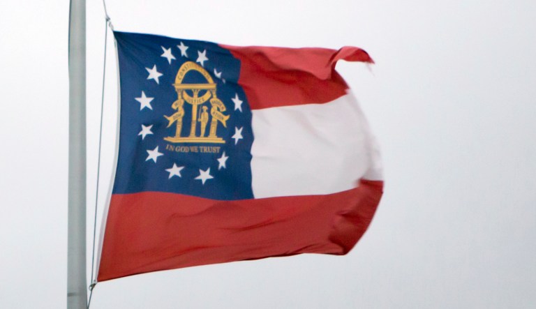 A flag of the U.S. state of Georgia is seen waving on a flagpole.