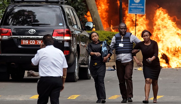 Security forces help civilians flee the scene as cars burn at a hotel complex in Nairobi, Kenya, Tuesday, Jan. 15, 2019.