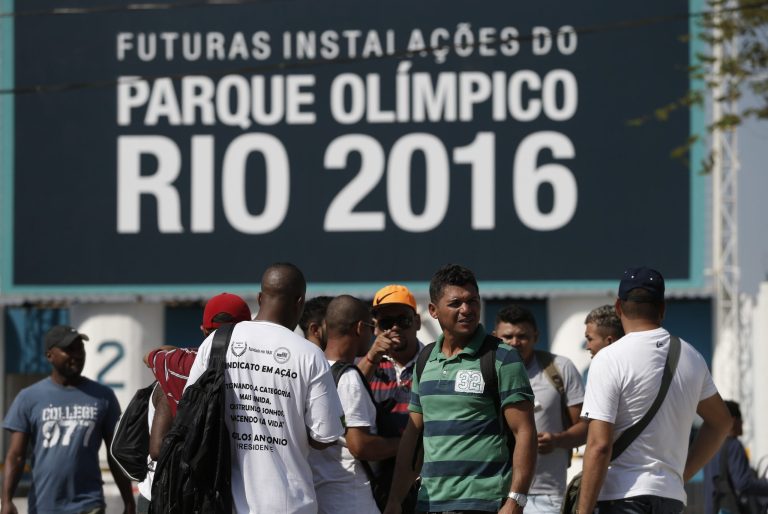 Striking workers stand in front the entrance of the Olympic Park, the main cluster of venues under construction for the 2016 Summer Olympic Games, in Rio de Janeiro, Brazil, Tuesday, April 8, 2014. The labor dispute centers around which union represents the construction workers, and also involves benefits and working conditions. (AP Photo/Silvia Izquierdo)