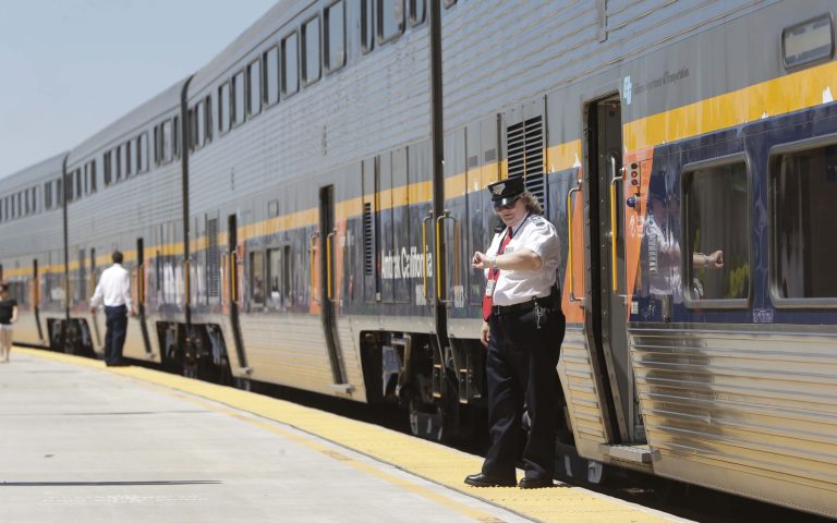 In this Tuesday, July 16, 2013, file photo, an Amtrak conductor checks the time as the passenger train takes on passengers in Hanford, Calif. (AP Photo/Rich Pedroncelli, File)