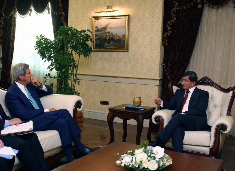 In this Friday, Sept. 12, 2014 photo released by the Turkish Prime Ministry, U.S. Secretary of State John Kerry, left, listens to Turkish Prime Minister Ahmet Davutoglu in Ankara, Turkey. Turkey is the big Muslim power that sits atop raging conflicts in Iraq and Syria, so it might be expected to take a leading role in the NATO coalition announced this month to take on the Islamic State group. Instead it told allies that it would stay quietly behind the scenes, keeping its soldiers out of combat operations and even declining to allow NATO to use its bases or territories to launch air attacks.(AP Photo/Turkish Presidency)