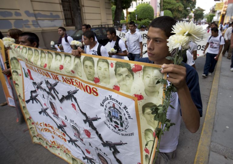 Students hold a banner withe faces of the missing that reads in Spanish 