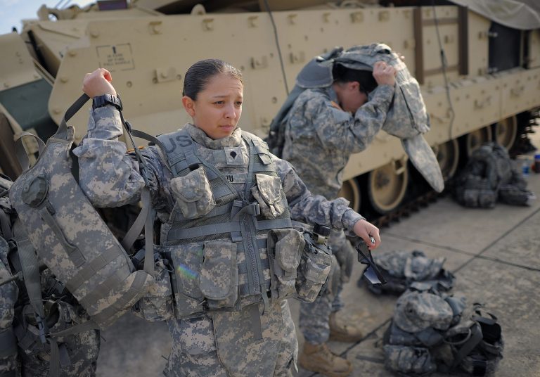 Spc. Karen Arvizu, left, puts on her hydration pack in preparation for her role as a volunteer in a physical demands study, Tuesday, Feb. 25, 2014, in Ft. Stewart, Ga. The Army is conducting a study that will determine how all soldiers, including women, for the first time, will be deemed fit to join its fighting units from infantry platoons to tank crews. (AP Photo/Stephen B. Morton)