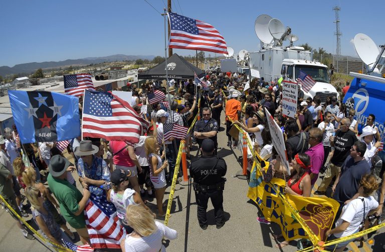 Demonstrators from opposing sides confront each other while being separated by Murrieta police officers Friday outside a U.S. Border Patrol station in Murrieta, Calif. (AP/Mark J. Terrill)