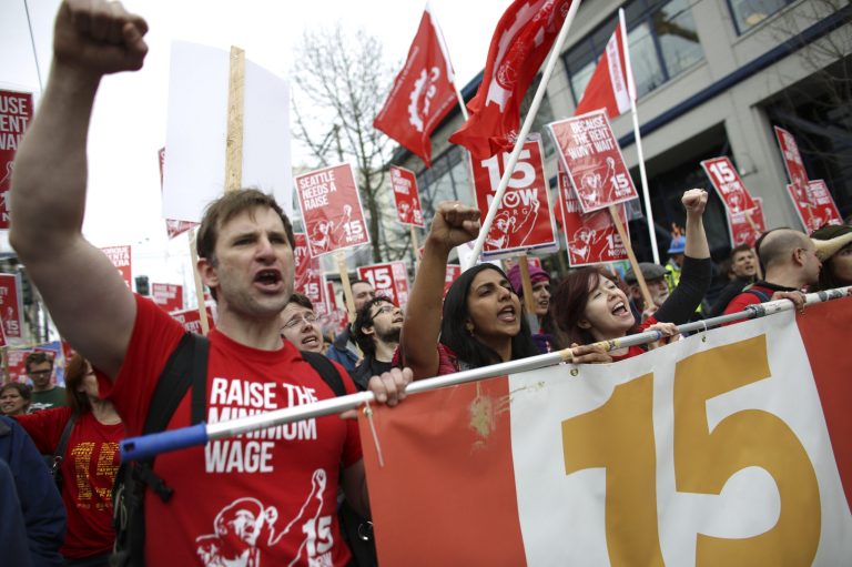 Organizer Bryan Watson, left, gestures during a march to raise the minimum wage to $15 per hour in Seattle. Seattle backers of a $15 minimum wage hike that would be the highest in the nation, are not slowing down after an election season last fall. Backers of the hike are threatening to put the question to voters next fall if the city council does no act quickly enough.