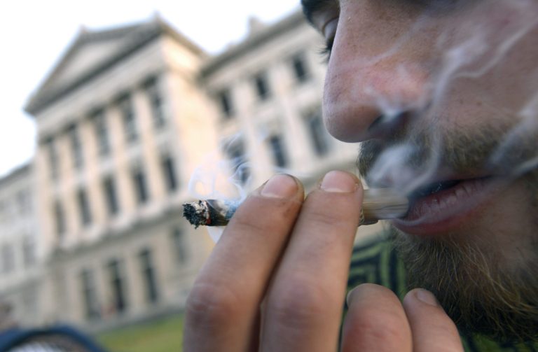 FILE - In this July 31, 2013 file photo, a man smokes a marijuana joint while Senators debate a bill at the Senate to legalize marijuana and regulate production and distribution in Montevideo, Uruguay. The South American country is still writing the rules for its legal marijuana market, two weeks overdue now, and President Jose Mujica has asked that no details be released until the regulations are finally published on Friday or Monday, April 28, 2014. (AP Photo/Matilde Campodonico, File)