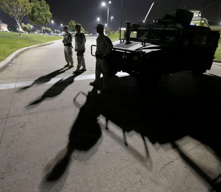 FILE - This Aug. 18, 2014 file photo shows members of the Missouri National Guard standing watch outside a command post near a protest for Michael Brown, who was killed by a police officer Aug. 9 in Ferguson, Mo. Brown's shooting has sparked more than a week of protests, riots and looting in the St. Louis suburb. Eric Holder, who is leading the federal response to the racial turmoil in Ferguson, Missouri, talks about the nation's civil rights struggles in a way none of the 81 previous U.S. attorneys general could _ by telling his own family story. (AP Photo/Charlie Riedel, File)