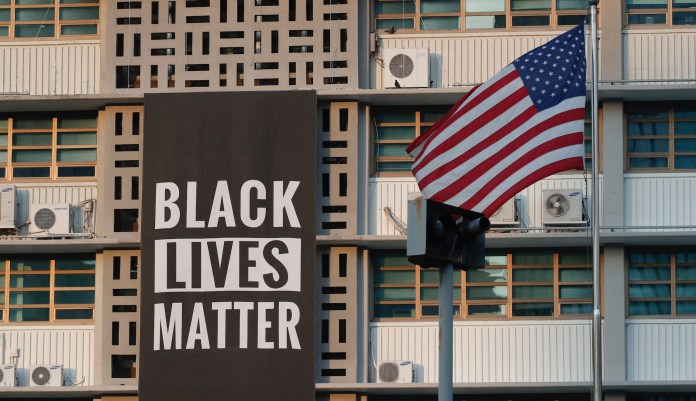 In this June 14, 2020 photo, U.S. flag flutters next to a giant Black Lives Matter banner at the U.S. Embassy in Seoul, South Korea.