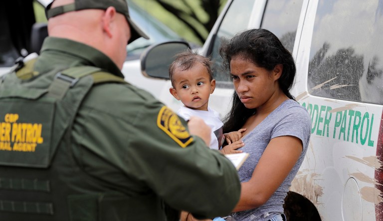A mother migrating from Honduras holds her 1-year-old child as surrendering to U.S. Border Patrol agents after illegally crossing the border Monday, June 25, 2018, near McAllen, Texas.
